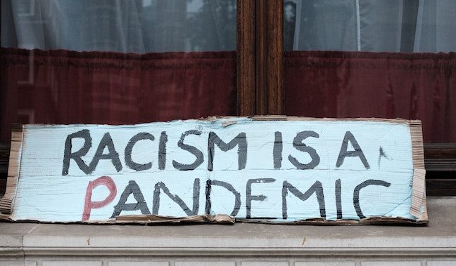 a sign that says racism is a pandemic