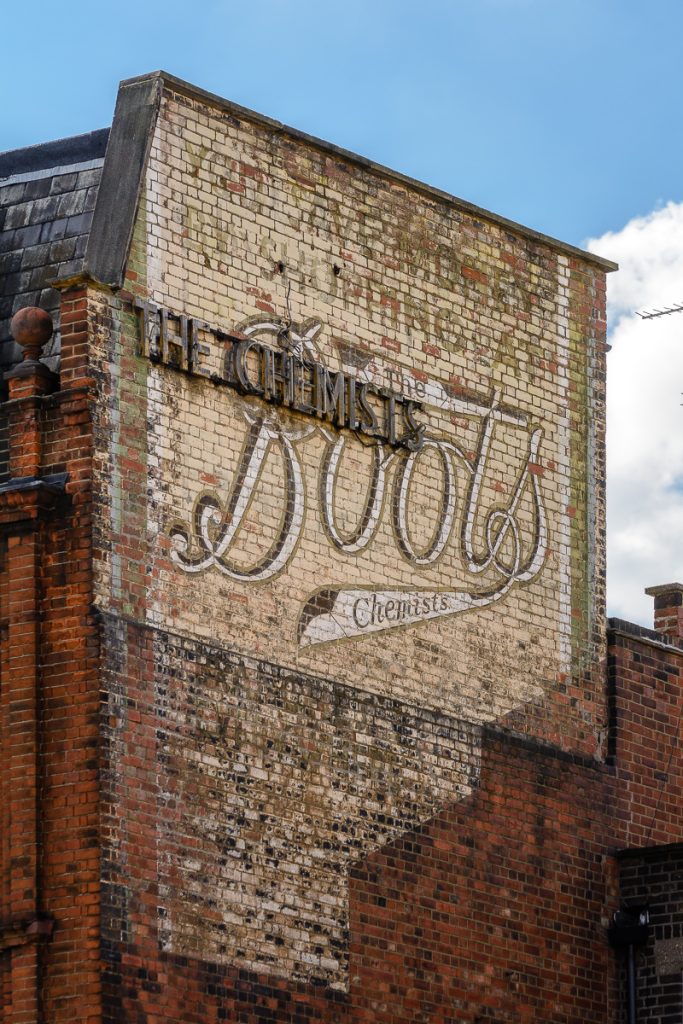 A wall with a faded version of the old Boots Chemist logo on it