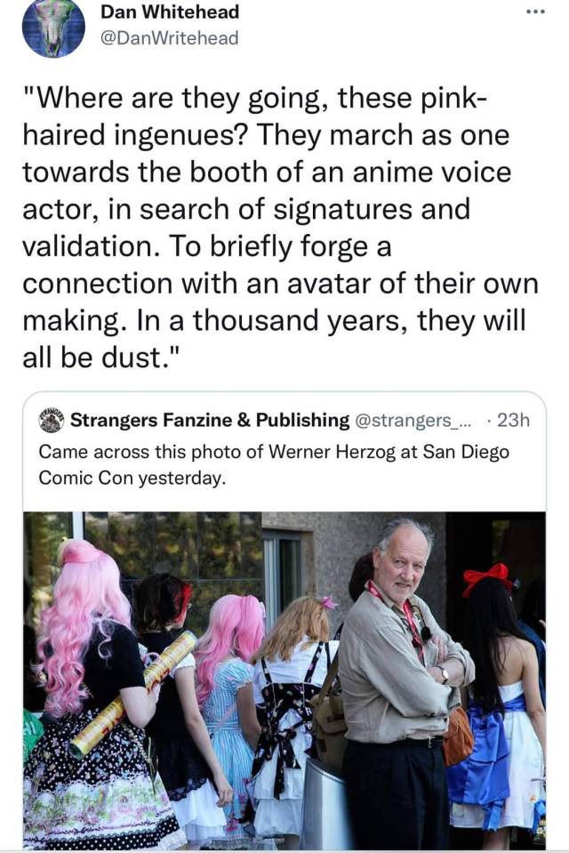 A picture of Werner Herzog at Comic Con with the quote tweet "Where are they going, these pink-haired ingenues? They march as one towards the booth of an anime voice actor, in search of signatures and validation. To briefly forge a connection with an avatar of their own making. In a thousand years, they will all be dust."