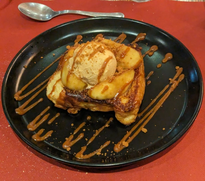 A Lost Brioche dessert featuring brioche bread, ice cream, and cooked apple slices, drizzled in caramel sauce
